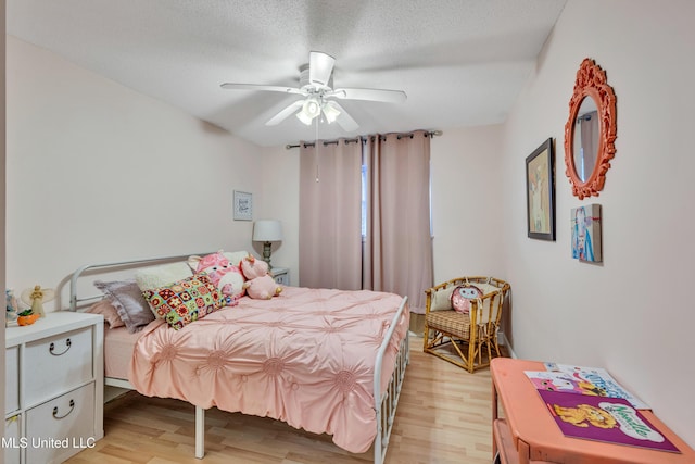 bedroom with a textured ceiling, a ceiling fan, and light wood-type flooring
