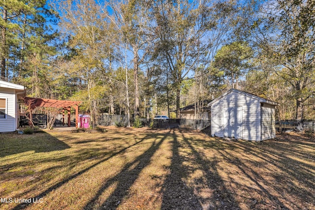 view of yard featuring an outdoor structure, a pergola, a storage unit, and fence