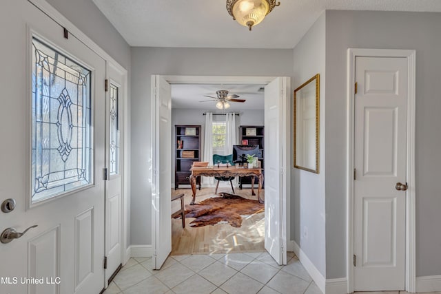 foyer entrance with light tile patterned floors, baseboards, and ceiling fan