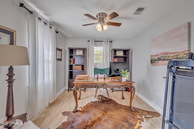 office space featuring light wood-type flooring, a textured ceiling, visible vents, and a ceiling fan
