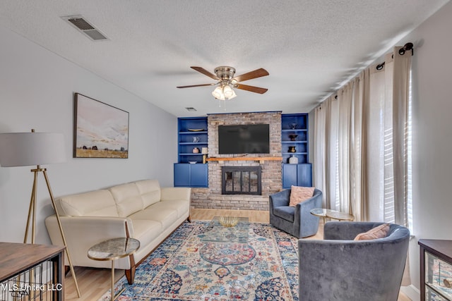 living area featuring a ceiling fan, wood finished floors, a textured ceiling, and visible vents