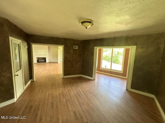 417 Boulevard St, Lexington, MS 39095 - unfurnished room with wood finished floors, baseboards, a textured ceiling, and a fireplace