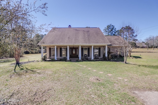 view of front facade with covered porch, roof with shingles, and a front yard