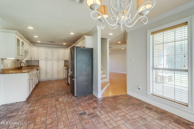 kitchen featuring brick floor, freestanding refrigerator, plenty of natural light, and a sink