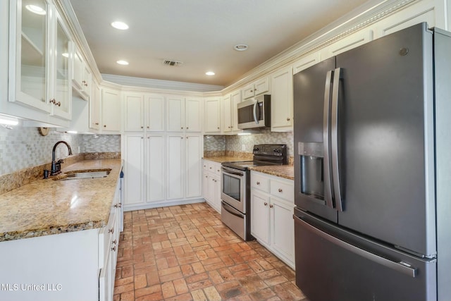 kitchen with stainless steel appliances, backsplash, brick floor, and a sink