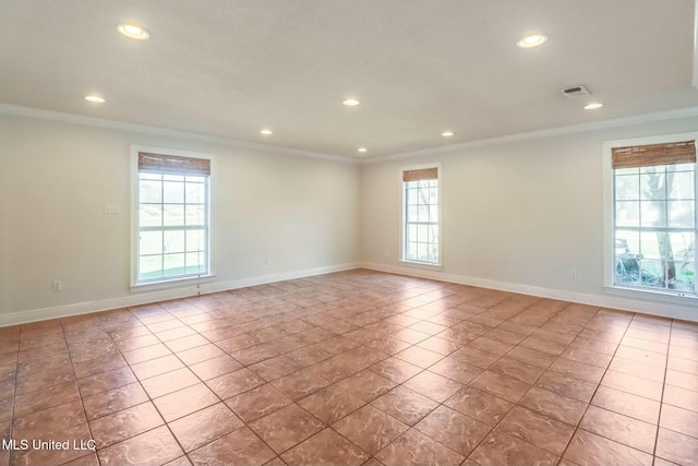 spare room featuring plenty of natural light, visible vents, and crown molding