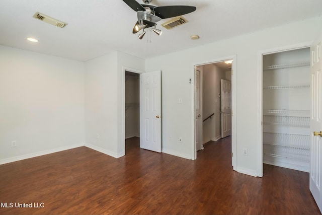 unfurnished bedroom with a spacious closet, a closet, wood finished floors, and visible vents