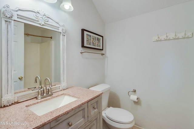 bathroom with vaulted ceiling, vanity, and toilet