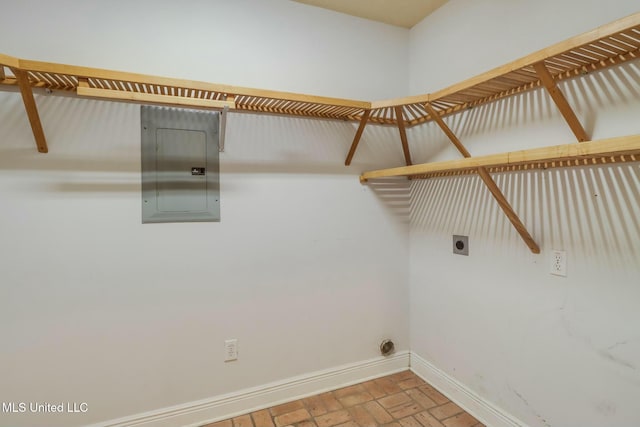 washroom with brick floor, hookup for an electric dryer, laundry area, baseboards, and electric panel