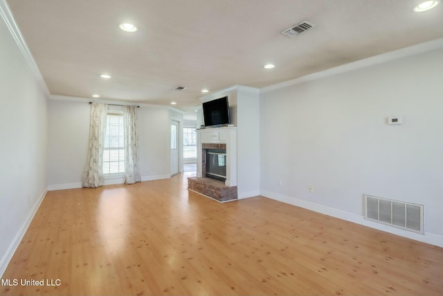 unfurnished living room with a brick fireplace, visible vents, light wood-style floors, and ornamental molding