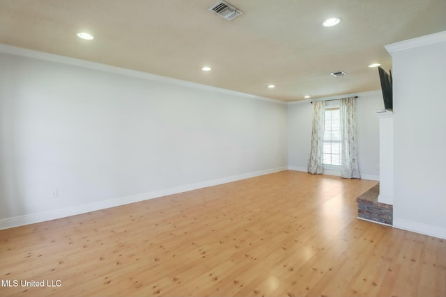 empty room with ornamental molding, visible vents, baseboards, and wood finished floors