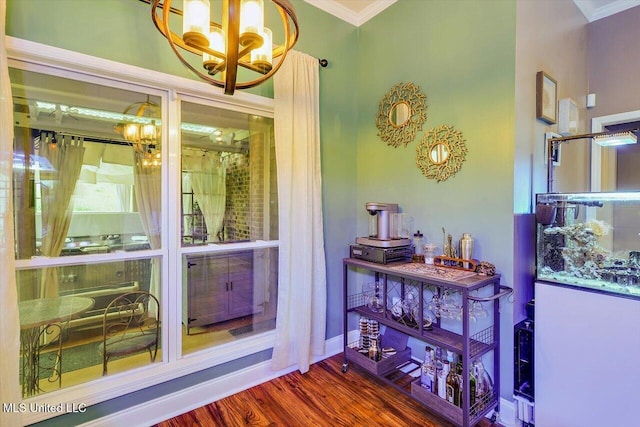 doorway to outside featuring a chandelier, ornamental molding, wood finished floors, and baseboards