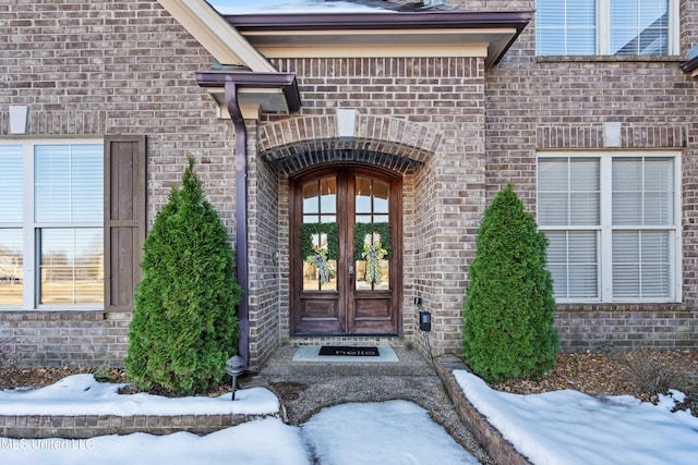 snow covered property entrance with french doors