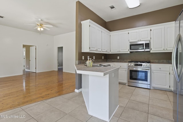 1013 Brashears Pt, Ridgeland, MS 39157 - kitchen with stainless steel appliances, a peninsula, white cabinetry, and light tile patterned floors