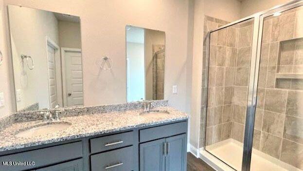 full bath with double vanity, a sink, and a shower stall