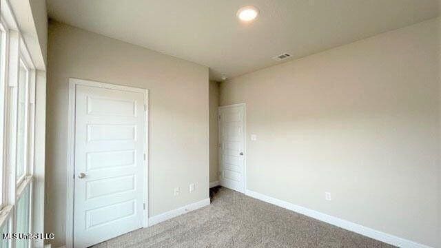 unfurnished bedroom with light carpet, visible vents, and baseboards