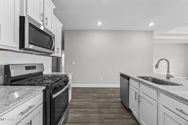 kitchen with white cabinets, decorative backsplash, light stone countertops, stainless steel appliances, and a sink