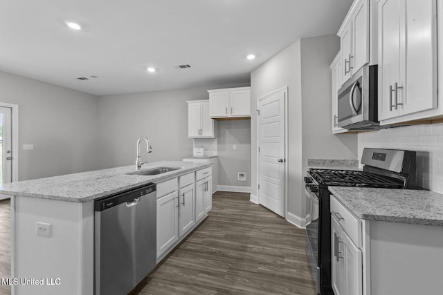 kitchen with an island with sink, appliances with stainless steel finishes, white cabinets, and a sink