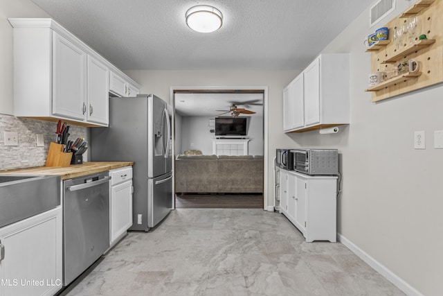 10510 Steeplechase Dr, Gulfport, MS 39503 - kitchen featuring stainless steel appliances, ceiling fan, white cabinets, a textured ceiling, and tasteful backsplash