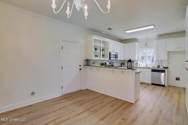 kitchen with light wood-type flooring, appliances with stainless steel finishes, light stone countertops, white cabinets, and kitchen peninsula