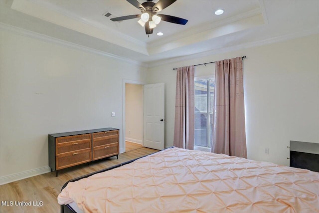 bedroom featuring light wood-type flooring, a tray ceiling, ceiling fan, and crown molding