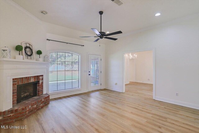 unfurnished living room with a brick fireplace, light wood-type flooring, ceiling fan with notable chandelier, and ornamental molding