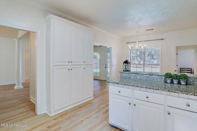 kitchen with pendant lighting, white cabinetry, light hardwood / wood-style floors, and ornate columns