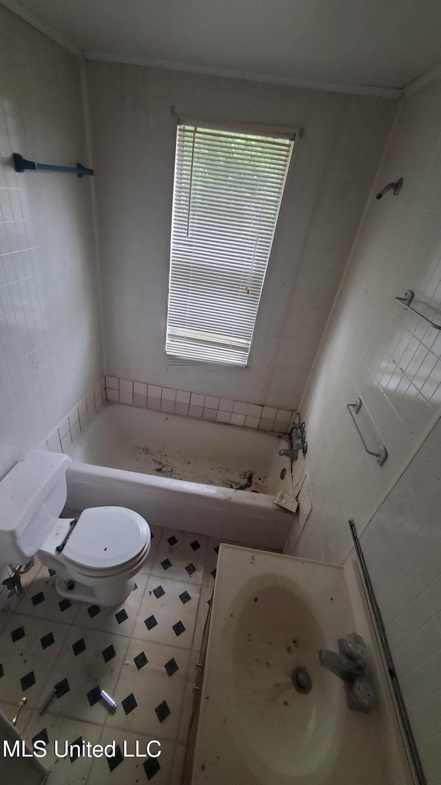 bathroom featuring a tub to relax in, tile patterned floors, and toilet