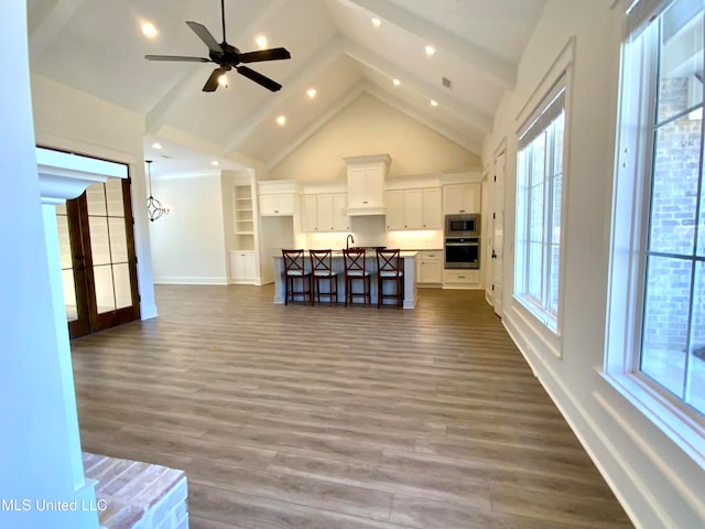 living room with beamed ceiling, ceiling fan, high vaulted ceiling, and dark hardwood / wood-style flooring