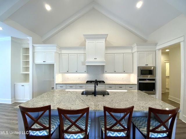 182 Sweetbriar Cir, Canton, MS 39046 - kitchen with stainless steel appliances, a sink, dark wood-style floors, white cabinets, and a breakfast bar