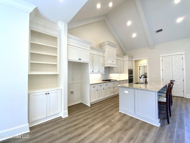 182 Sweetbriar Cir, Canton, MS 39046 - kitchen featuring white cabinets, a sink, a center island with sink, wood finished floors, and high vaulted ceiling