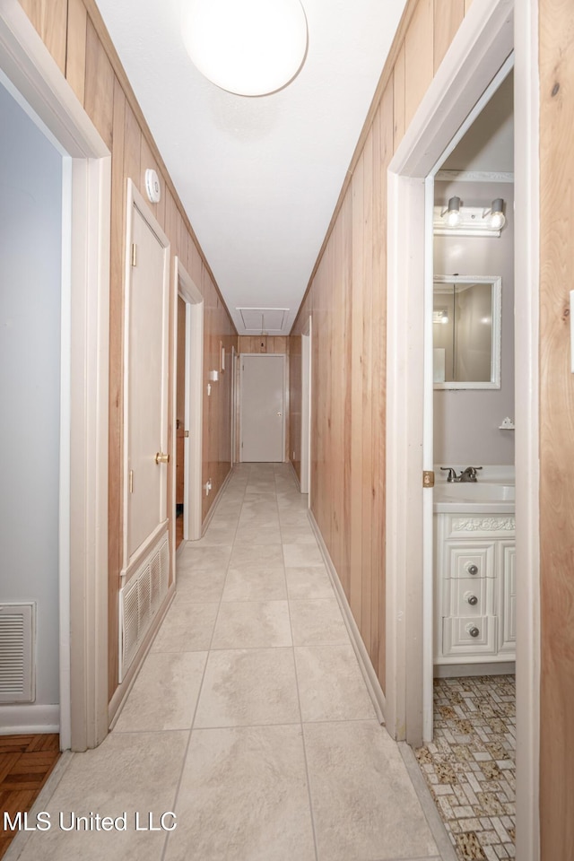 hallway with wood walls, crown molding, and light tile patterned floors