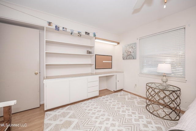 office space featuring built in desk, light hardwood / wood-style floors, and ceiling fan