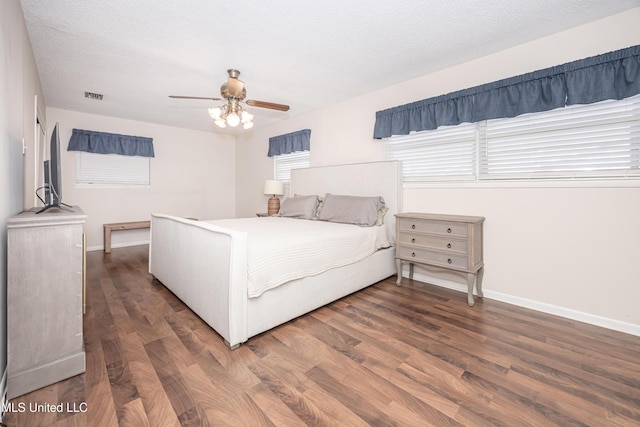 bedroom with a textured ceiling, ceiling fan, and dark wood-type flooring