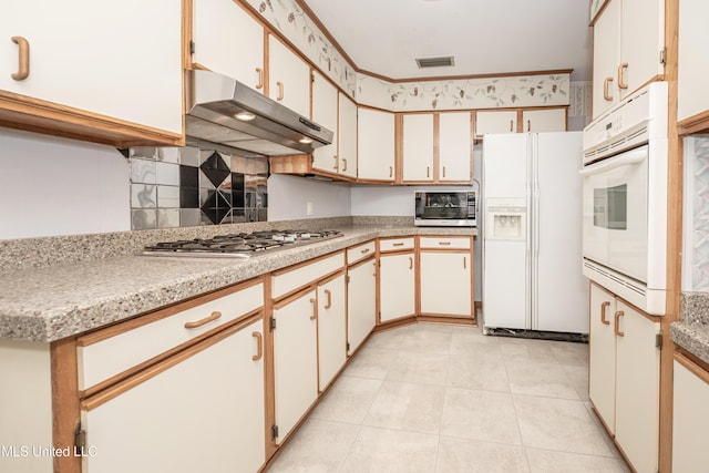 kitchen featuring appliances with stainless steel finishes, light tile patterned floors, and white cabinetry