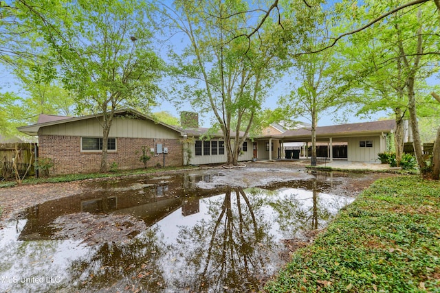 43 Greenbriar Dr, Gulfport, MS 39507 - rear view of property featuring board and batten siding, a chimney, fence, and brick siding