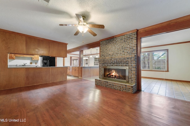 43 Greenbriar Dr, Gulfport, MS 39507 - unfurnished living room with a fireplace, a textured ceiling, wood finished floors, and a ceiling fan