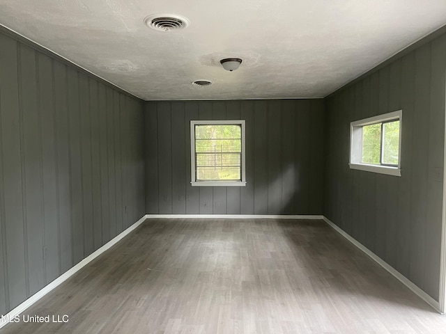 2938 Oak Forest Dr, Jackson, MS 39212 - spare room featuring wood finished floors, healthy amount of natural light, wood walls, and a textured ceiling