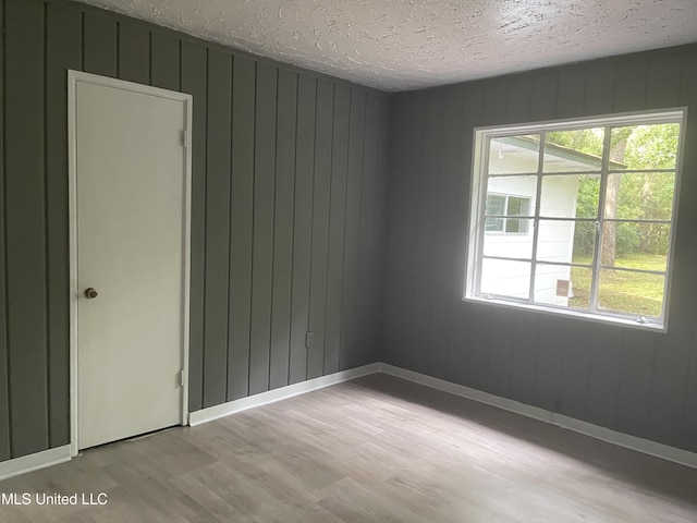 2938 Oak Forest Dr, Jackson, MS 39212 - spare room with light wood-style flooring, a textured ceiling, and wooden walls