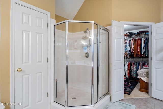 bathroom featuring a shower with door, tile patterned floors, and vaulted ceiling