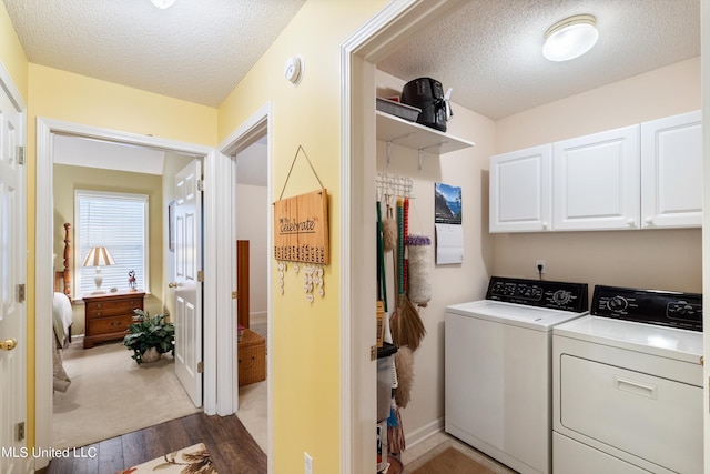 washroom featuring cabinets, a textured ceiling, washing machine and dryer, and dark hardwood / wood-style flooring