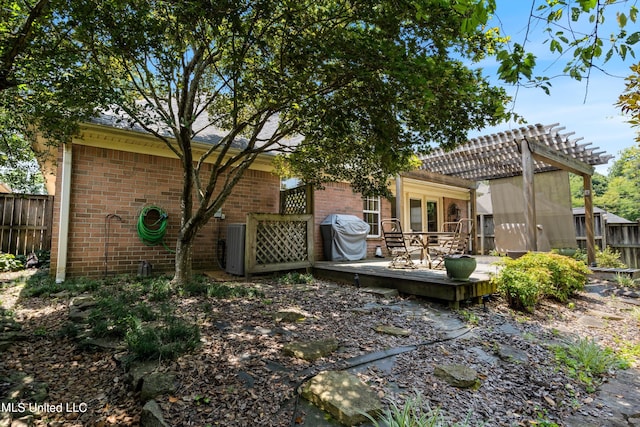 back of property featuring a wooden deck and a pergola