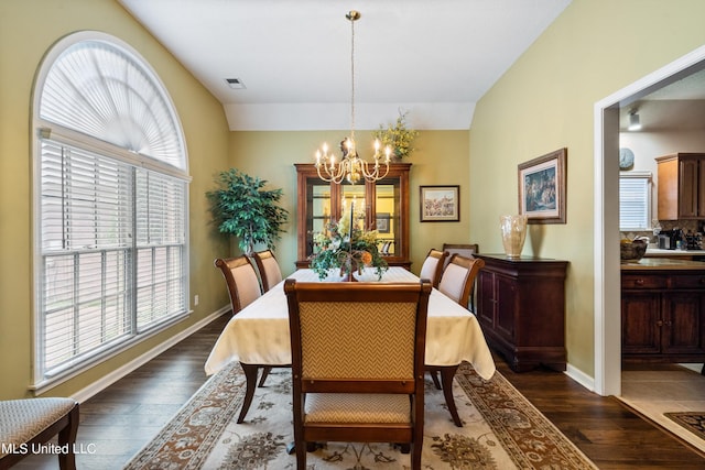 dining room with lofted ceiling, a healthy amount of sunlight, and dark hardwood / wood-style flooring