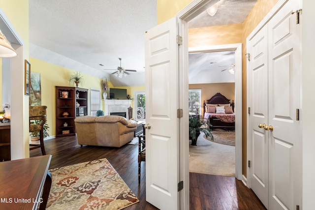 living room with dark wood-type flooring, ceiling fan, and a textured ceiling