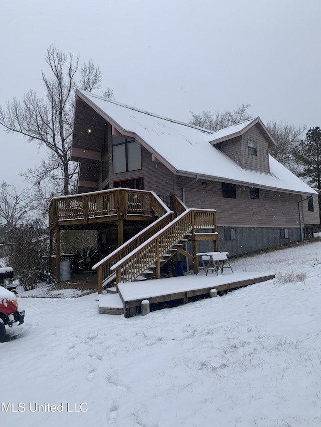 snow covered back of property with a deck