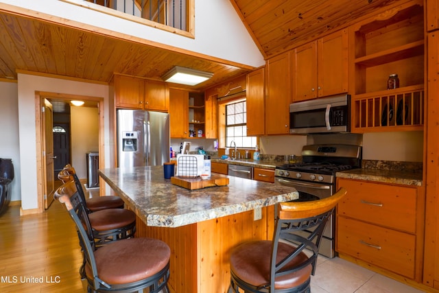 kitchen featuring appliances with stainless steel finishes, a kitchen breakfast bar, a kitchen island, vaulted ceiling, and wooden ceiling