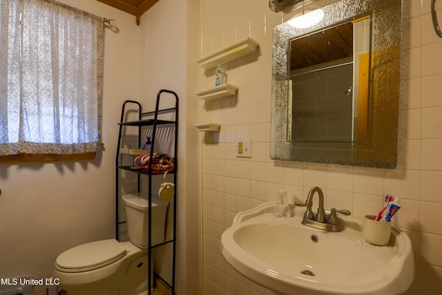 bathroom with walk in shower, toilet, sink, tile walls, and backsplash