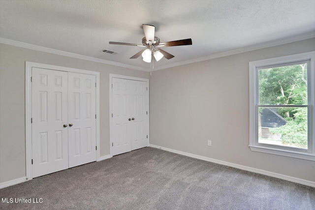 unfurnished bedroom featuring multiple closets, light carpet, and ceiling fan