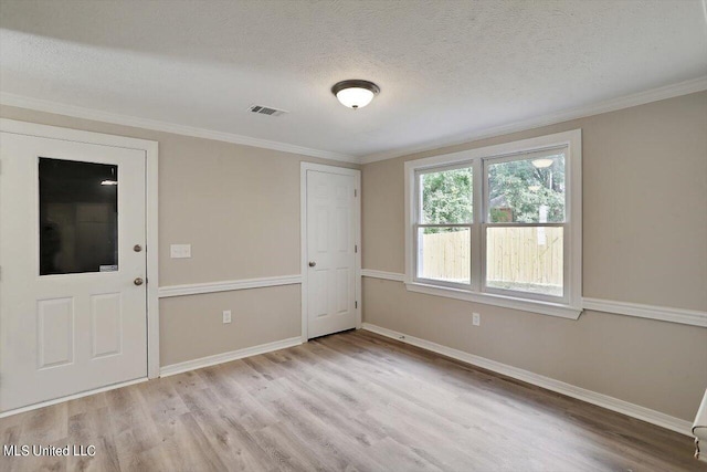 spare room with ornamental molding, light hardwood / wood-style flooring, and a textured ceiling