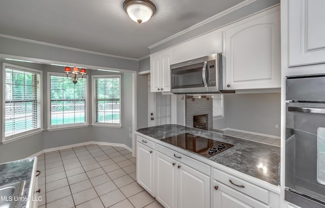 kitchen featuring black appliances, crown molding, a brick fireplace, light tile patterned flooring, and white cabinetry